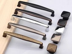 several different types of door handles on a white surface with wood and metal pulls in the middle