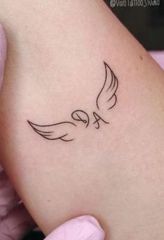 a small tattoo on the back of a woman's left arm, with a bird flying