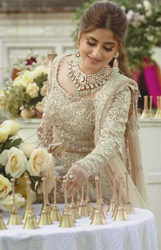 a woman standing in front of a table filled with gold candles and white roses on it