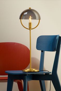 a chair with a lamp on top of it next to a blue table and red chair