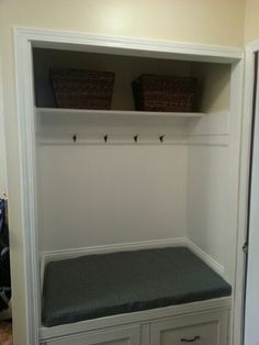 a bench with two baskets on top of it in a room that is painted white