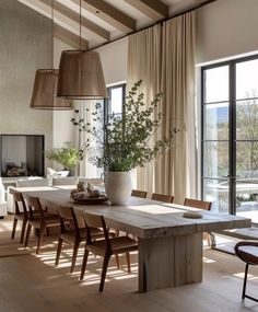 a dining room table and chairs in front of large windows