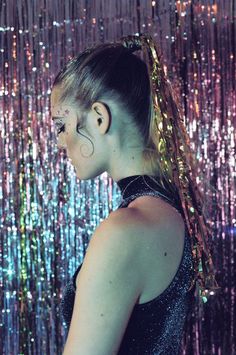 a woman standing in front of a wall covered with sequins