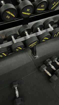 rows of black dumbbells in a gym with yellow lettering on the side and two rows of black dumbbells behind them