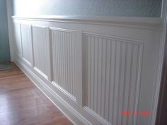 an empty room with wood floors and white paneling