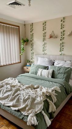 an unmade bed sitting in a bedroom next to a window with plants on the wall