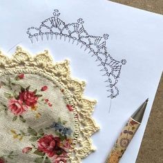 a piece of paper with an embroidered doily on it next to a crocheted pen