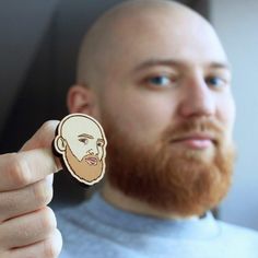 a man with a beard holding up a wooden sticker