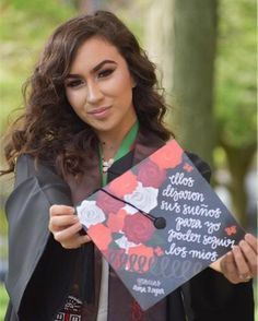 a woman holding up a graduation cap with writing on the front and side of it