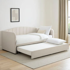 a white bed sitting on top of a hard wood floor next to a large window