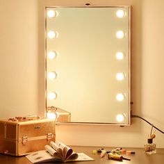 a vanity mirror sitting on top of a wooden desk next to a book and lamp