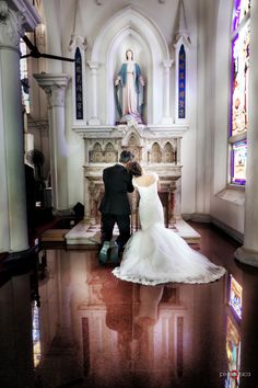 a bride and groom kneeling in front of the alter