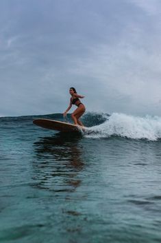 a woman riding a surfboard on top of a wave in the middle of the ocean