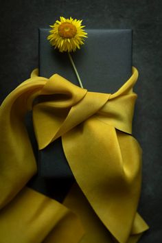 a yellow flower sitting on top of a black box