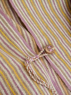 a close up of a button on a pink and white striped shirt with yellow stripes