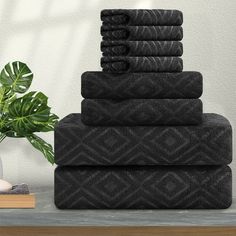 a stack of black towels sitting on top of a table next to a potted plant