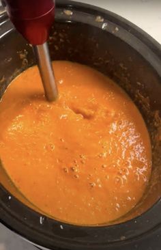 an orange sauce being stirred in a pot