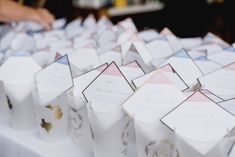 many small boxes are lined up on a table with white linens and gold foil