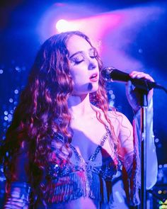 a woman with long red hair singing into a microphone