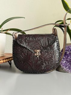 (Primary color is dark brown). Beautiful, yet durable, thick genuine leather hand tooled in Mexico using the "cincelada" technique. Removable adjustable shoulder strap and latch closure. Dimensions: 8.5" L x 7.5" W x 3'' H. Please check size dimensions before ordering.  Imported from Mexico, they are a continuation of the fine craftsmanship established in that country going back hundreds of years with carved leather saddles. These beauties are not like the more common stamped products that can b Artisan Hand Tooled Leather Saddle Bag, Artisan Hand-tooled Leather Saddle Bag, Artisan Brown Embossed Shoulder Bag, Brown Engraved Leather Shoulder Bag, Traditional Brown Embossed Bags, Brown Leather Engraved Shoulder Bag, Brown Engraved Bags For Everyday Use, Engraved Brown Bags For Everyday Use, Hand Tooled Brown Leather Saddle Bag