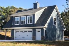 a gray house with white windows and two garages