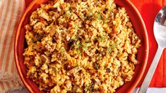 a bowl filled with rice and meat on top of a table next to a fork