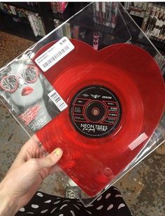 a person holding up a red vinyl record in a clear box with the label on it