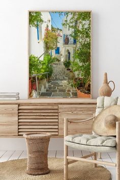 a room with a chair, potted plant and an art print on the wall