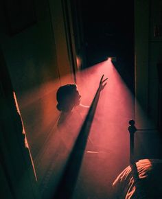 a person standing in the dark with their arm raised up and light coming from behind them