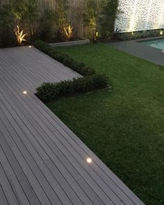 a wooden deck in the middle of a yard with lights on it's sides