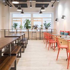 an empty restaurant with wooden tables and orange chairs in front of large windows on the wall