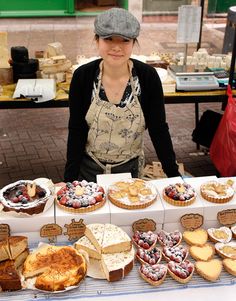 a woman standing in front of a table filled with pastries