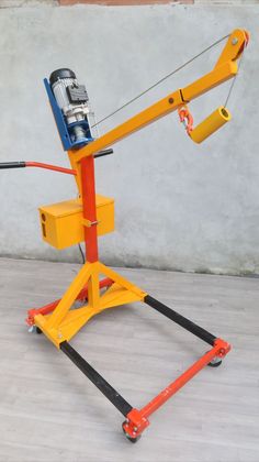 an orange and black machine on top of a wooden floor next to a cement wall