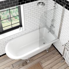 a white bath tub sitting on top of a wooden floor next to a radiator