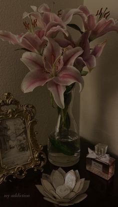 there is a vase with pink flowers in it on the table next to a mirror