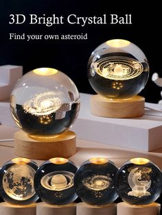 three crystal balls on wooden bases with gold and black designs in the center, surrounded by other glass orbs