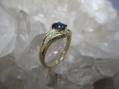 This 14K Gold Ring is set with a beautiful gem grade Sapphire and accented with Diamonds. The Oval Cut Sapphire has great blue color. Not too dark and not too light. It measures 5.5 mm by 4.5 mm and weighs .66 carat. It is a clean, well cut natural stone. There are 8 accenting Diamonds, 4 on each side. The accent Diamonds weigh .05 carat total weight. The ring is about 5/16 inch wide on top and tapers to a narrow band in the back. Low profile settings make this a very wearable ring. It is made i Yellow Gold Sapphire Ring With Gemstone Accents, Round Cut Topaz Ring With Gemstone Accents, Fine Jewelry Sapphire Birthstone Ring With Gemstone Accents, Sapphire Birthstone Ring With Gemstone Accents, Formal Pear-shaped Sapphire Ring With Accent Stones, Blue Marquise Cut Diamond Ring With Accents, Formal Sapphire Birthstone Ring With Accent Stones, Promise Ring Diamond With Gemstone Accents, Diamond Birthstone Ring With Gemstone Accents