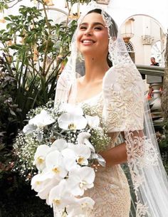 a woman in a wedding dress holding a bouquet of white flowers and posing for the camera