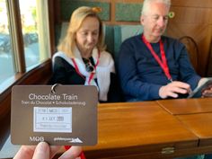 a man and woman sitting at a table with a chocolate train card in front of them