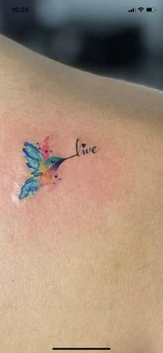 a small tattoo on the back of a woman's left shoulder that says live