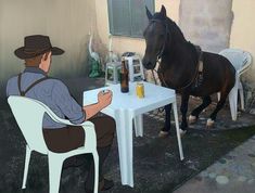 a man sitting at a table with a horse next to him and a bottle of beer