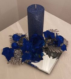 a blue candle sitting on top of a table next to some flowers and a mirror