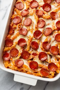 a white casserole dish filled with pepperoni and cheese