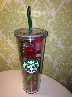 a starbucks cup with red and green straws in it on top of a table