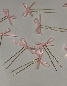 several pink bows and pins on a white surface