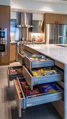 an open drawer in the middle of a kitchen with stainless steel appliances and counter tops