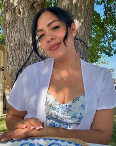 a woman sitting at a table in front of a tree