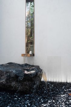 a black rock sitting under a mirror next to a wall mounted faucet in a white walled room