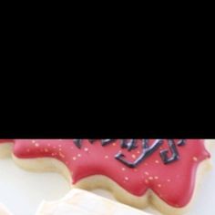 two decorated cookies sitting next to each other on top of a white tablecloth covered surface