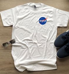 NASA Meatball Insignia logo T-Shirt. These tees have the small Meatball Logo on the left portion of the chest. Available in White, contact us a size chart if needed. We also carry Hoodies, Sweatshirts, long sleeves, toddler and baby sizes too! Each item is designed and printed in the Portland with high quality workmanship. These NASA Meatball Insignia Tees are 100% air-lume combed, ring-spun cotton, fashion tees that are super soft and comfortable. They're a fashion fit with a slightly higher ar Space Tee, Nasa Shirt, Cotton Fashion, Color Swatch, Fashion Fits, Baby Size, All Colors, Fashion Tees, Tshirt Logo